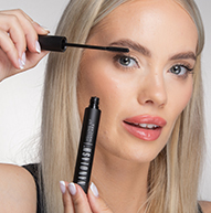En kvinne påfører forsiktig mascara på øyevippene, og holder børsten nært for en perfekt finish.