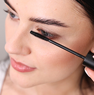 En kvinne bruker dyktig en mascarabørste for å påføre mascara, med fokus på øyevippene for å oppnå et definert utseende.